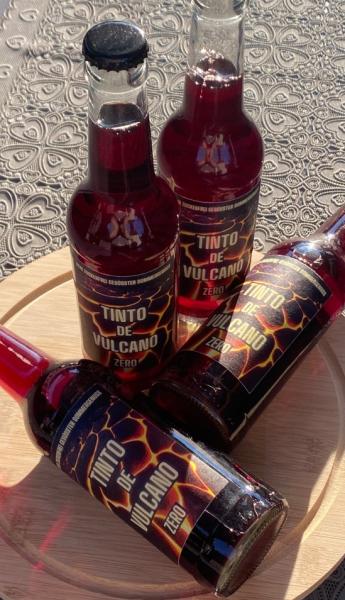 Flaschen mit Etikett mit einer roter Flüssigkeit Tinto de Vulcano Zero, auf einem Brett angerichtet
